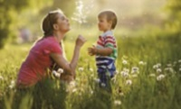 woman blowing bubbles with toddler boy